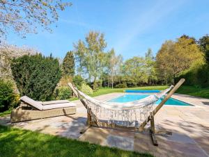 a hammock and a chair next to a swimming pool at Brooks Farmhouse - Pulborough in Pulborough