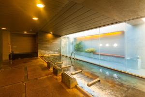 a swimming pool with benches in a building at Dormy Inn Kanazawa Natural Hot Spring in Kanazawa