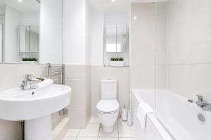 a white bathroom with a sink and a toilet and a tub at Roomspace Serviced Apartments - Abbot's Yard in Guildford +11 photos