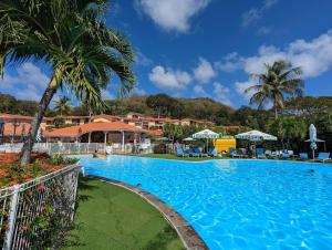 a pool at a resort with palm trees and buildings at Ti' Cocon Caritan in Sainte-Anne