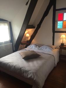 a bedroom with a large white bed with two windows at La Régissière in Vatteville
