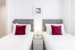 two beds with red pillows sitting next to each other at Roomspace Serviced Apartments - Abbot's Yard in Guildford