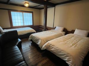 a hotel room with two beds and a couch at Matsunokitei Chalet Irori in Otari