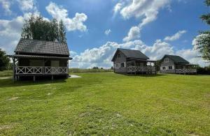 two houses on a green field with a blue sky at Przystanek Rydzówka - domki na Mazurach in Srokowo