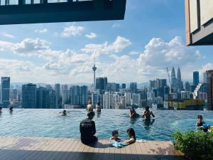 a group of people in a infinity pool with a city skyline at Lucentia Residence BBCC Modern City View Stay in Kuala Lumpur