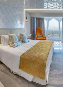 a bedroom with a large bed with an orange chair at Hotel teara in Gwalior