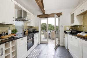 a kitchen with white cabinets and an open door at Perry Cottage in Halford
