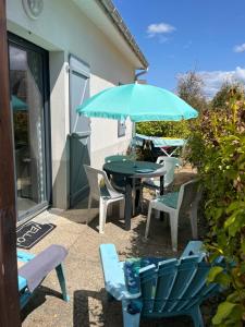 a patio with a table and chairs and an umbrella at val Queven in Quéven