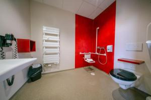 a bathroom with a toilet and a red wall at Hostellerie Bon Pasteur in Angers +41 photos