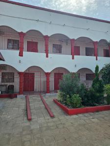 a building with red doors and windows and some plants at Kaira kunda guesthouse in Nimsat
