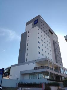 a large white building with a blue sign on it at Summit Suítes Hotel Pindamonhangaba in Pindamonhangaba