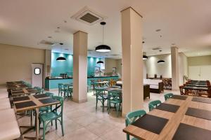 a dining room with tables and chairs and a cafeteria at Summit Suítes Hotel Pindamonhangaba in Pindamonhangaba