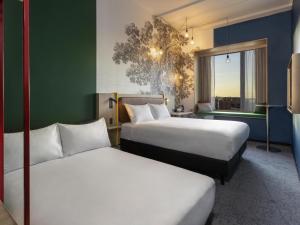 a hotel room with two beds and a window at ibis Styles Copenhagen Orestad in Copenhagen
