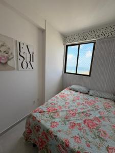 a bedroom with a bed with a floral bedspread and a window at Summer house in Olinda
