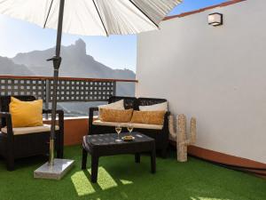 a balcony with chairs and an umbrella and a table at Casa Ada con Terraza Panorámica al Roque Bentayga by Canarias Prime Homes in Tejeda