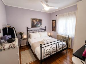 a bedroom with a bed with white sheets and a fan at The Secret Garden Peraia in Perea