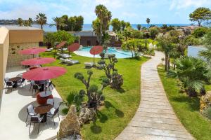 a patio with tables and umbrellas and a pool at Zurafa Resort in Terrauzza