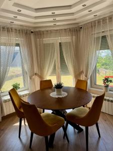 a dining room with a table and chairs and windows at SAN Apartments Near Belgrade Airport in Surčin