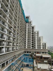 a large building with a swimming pool in front of it at Sunlit Omaxe ITC, Greater Noida in Greater Noida
