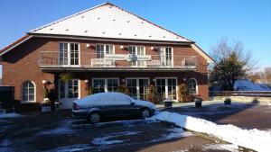 um carro estacionado em frente a uma casa de tijolos com neve em Hotel und Restaurant Rabennest am Schweriner See em Raben Steinfeld