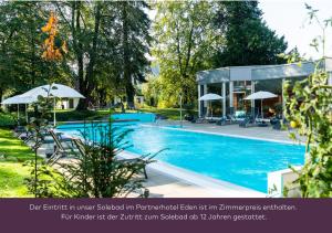 a swimming pool with chairs and umbrellas next to a building at Hotel Schiff am Rhein in Rheinfelden