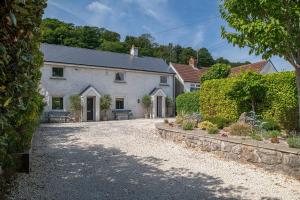 a large white house with a gravel driveway at Bayholme House in Oxwich