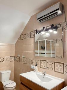 a bathroom with a sink and a toilet and a mirror at Loft Boutique con Encanto in Montilla