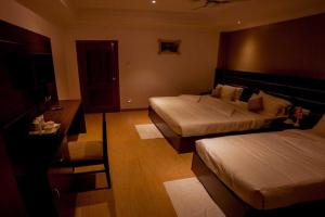 a hotel room with two beds and a desk at Matha Residency Munnar in Suryanelli