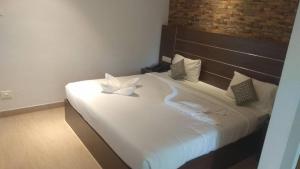 a bedroom with a bed with white sheets and pillows at Matha Residency Munnar in Suryanelli