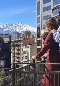 a woman standing on a balcony with a glass of wine at Bellas Artes Palace Secret Suites Adult Only in Santiago