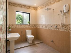a bathroom with a toilet and a sink and a window at The Kandyan Nest in Kundasale