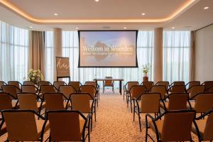 a room with a stage and chairs and a screen at Van der Valk Hotel Woerden in Woerden