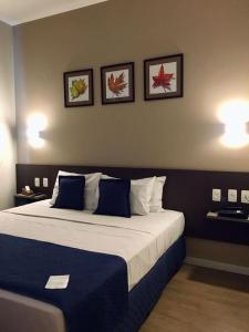 a bedroom with a large bed with three pictures on the wall at Summit Suítes Hotel Pindamonhangaba in Pindamonhangaba +16 photos