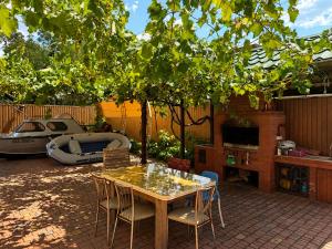 a patio with a table and chairs under a tree at Дом рыбака Маяки Ватер Сити Днестр in Mayaki