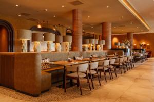 a restaurant with a long bar with chairs and tables at Van der Valk Hotel Woerden in Woerden