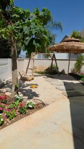 a garden with a tree and an umbrella and flowers at הבקתות במושבה in Rosh Pinna