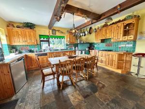 a kitchen with wooden cabinets and a table and chairs at Rainbow Cottage Glenmore in Dundalk