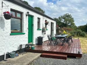 a house with a wooden deck with a table and chairs at Rainbow Cottage Glenmore in Dundalk