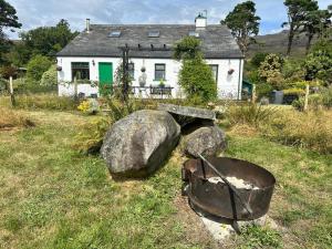 a white house with a building with a pot and some rocks at Rainbow Cottage Glenmore in Dundalk
