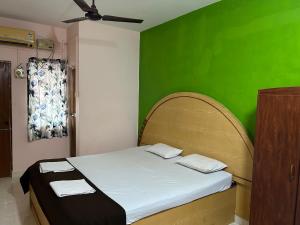 a bedroom with a bed with a green wall at Cassa ff guesthouse in Palolem