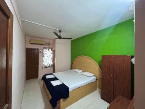 a small room with a bed and a green wall at Cassa ff guesthouse in Palolem