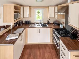 a kitchen with white cabinets and wooden floors at 86 Cader Idris in Pwllheli