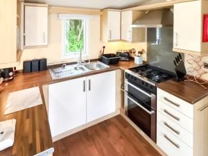 a kitchen with white cabinets and a stove at 86 Cader Idris in Pwllheli