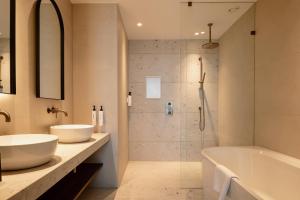 a bathroom with two sinks and a tub and a shower at Van der Valk Hotel Woerden in Woerden +37 photos
