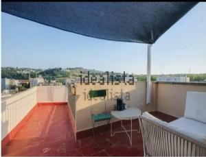 a balcony with a couch and a table on a roof at Where Mediterranean colours meets you in Terrassa