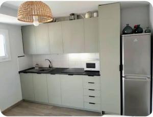 a kitchen with white cabinets and a stainless steel refrigerator at Where Mediterranean colours meets you in Terrassa