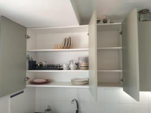 a kitchen with white cabinets with plates and utensils at Where Mediterranean colours meets you in Terrassa