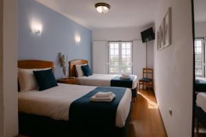a hotel room with two beds and a window at Hospedaria Canto do Rossio in Vidigueira