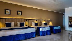 two beds in a hotel room with blue and white at Summit Beach Hotel Boiçucanga in Boicucanga +36 photos