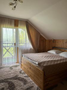 a bedroom with a bed and a large window at Respect in Mykulychyn